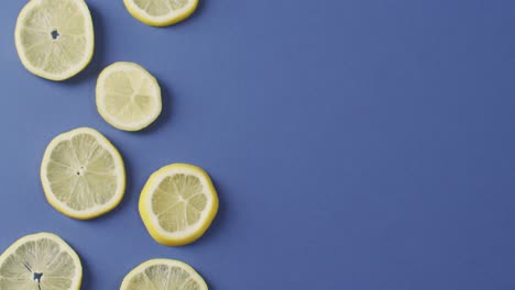 video of slices of lemon lying on blue background with copy space