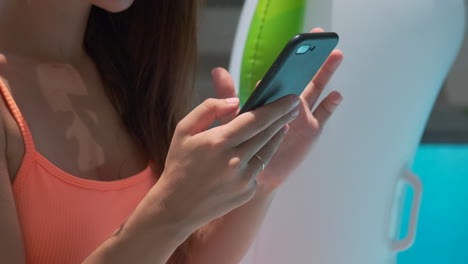 mujer usando el teléfono junto a la piscina