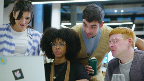 cheerful coworkers using laptop and discussing business ideas in the office