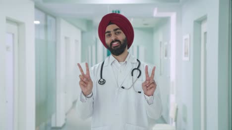 Glücklicher-Indischer-Sikh-Arzt,-Der-Siegeszeichen-Zeigt