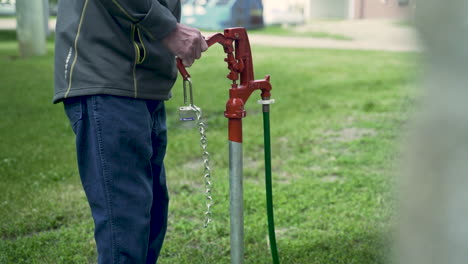 slow-motion shot of man pumping water spigot in garden field