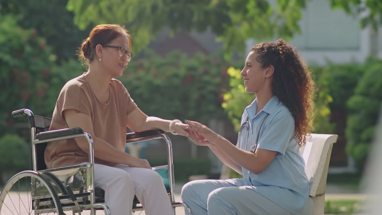 Nurse assisting elderly woman in wheelchair in a park
