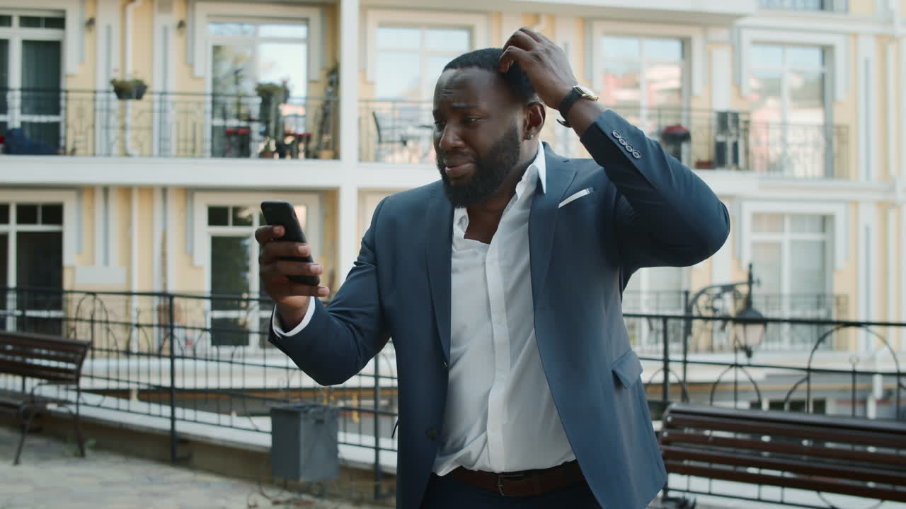 Upset afro business man getting bad news outdoors