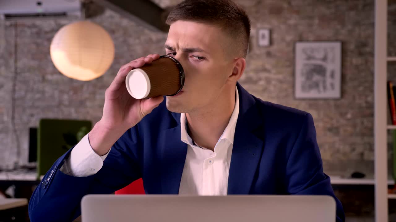 Young serious businessman is watching in laptop, drinking coffee, communication concept, business concept