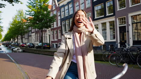 happy woman cycling along a canal in amsterdam