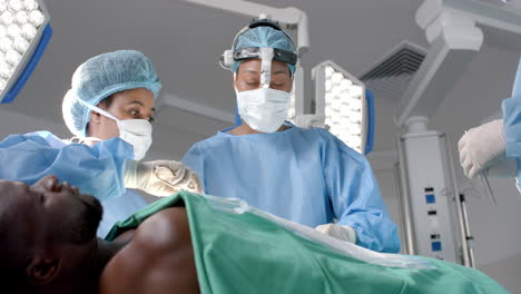 diverse female surgeons operating on african american patient in operating theatre, slow motion