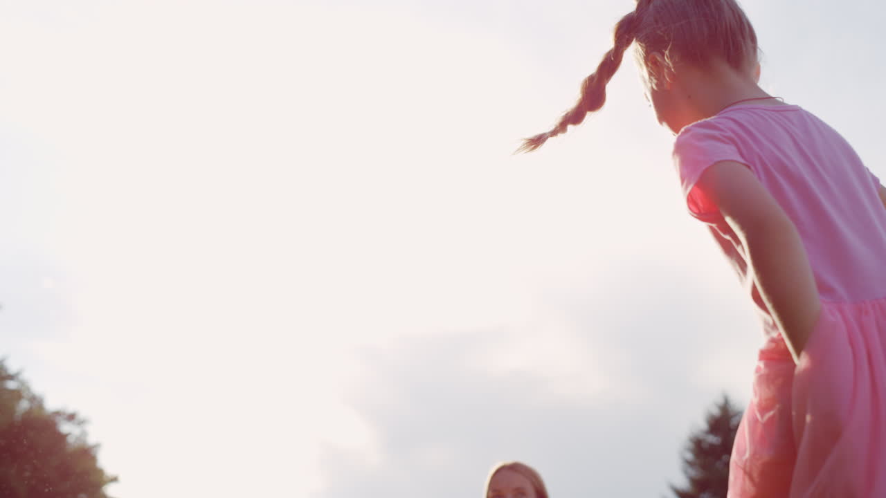 Donna allegra che soffia bolle nel parco cittadino. Bambina gioiosa che si diverte all'aperto.