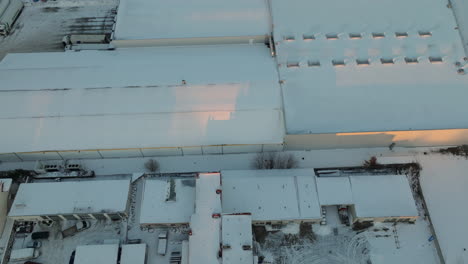 snow blankets the rooftops of buildings in dąbrowa, gdynia, with the soft hues of dawn reflecting off the white surfaces, creating a quiet and tranquil urban winter scene