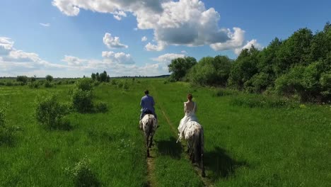 una pareja montando caballos en un campo.