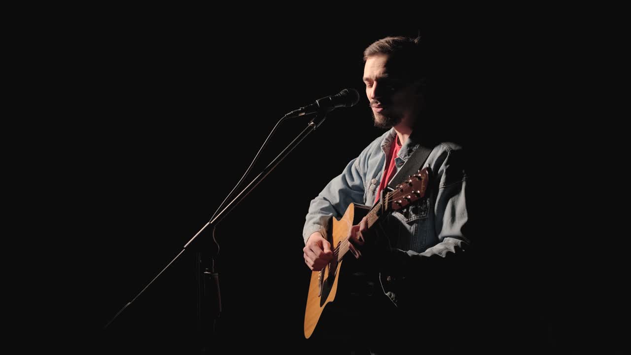 A musician is playing guitar on a large stage with audience members holding flashlights in the background. The auditorium is filled with beautiful flashing lights.