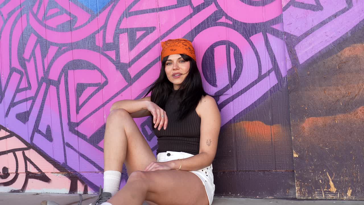 Young Woman Smiling and Posing Against a Vibrant Graffiti Wall