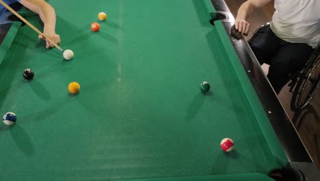 adult men with disabilities in a wheelchair play billiards in the club