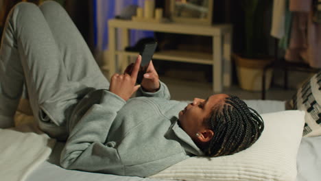 woman using phone in bed at night