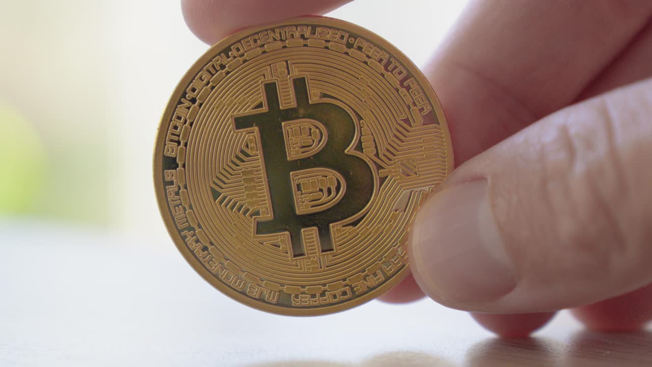 slow motion shot of a person holding a bitcoin within their hands