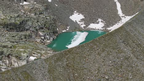 Flying-over-green-hidden-isolated-lake-of-Fellaria-glacier-in-Valmalenco-of-Valtellina-region,-Italy