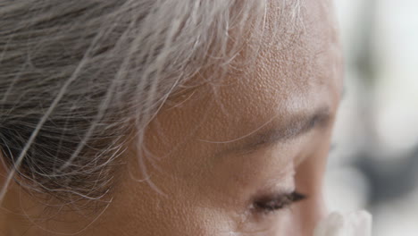 close up of face of unhappy middle aged woman crying and drying her tears with tissue