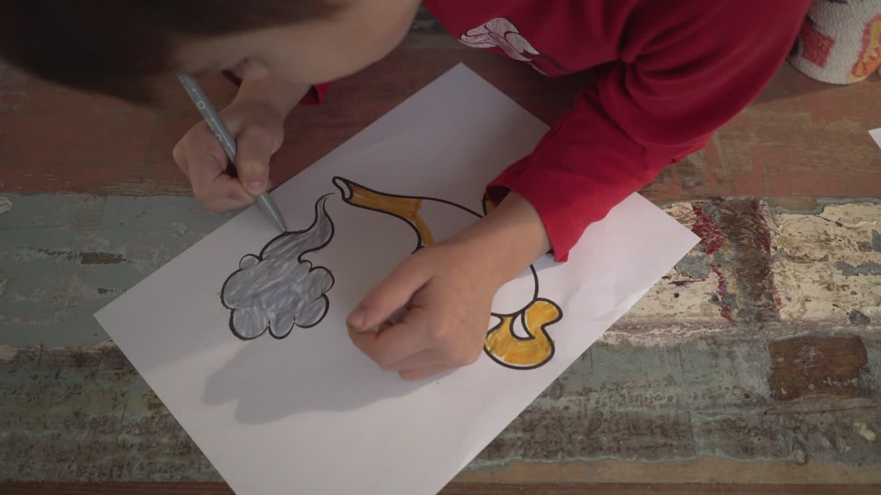 Caucasian boy painting a magic lamp draw using a grey marker indoors, high view close up 4K