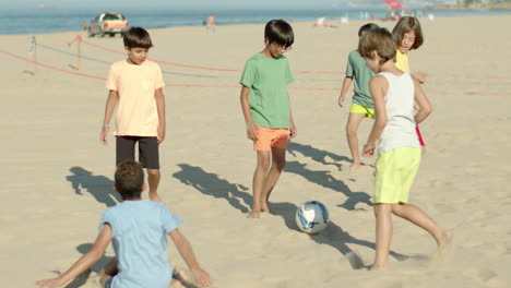 slow motion of boys playing football on beach on summer day