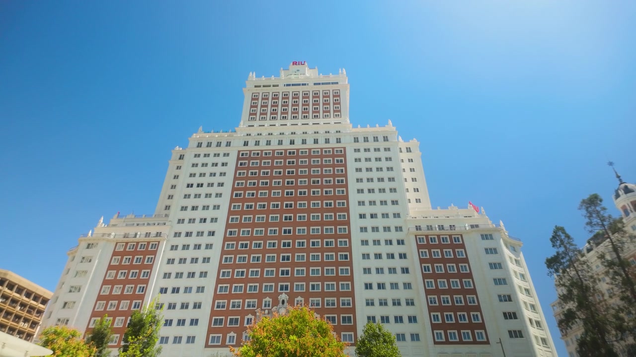 Uma vista de baixo ângulo do icônico arranha-céu Edifício España contra um céu azul claro em Madrid, Espanha. Útil para documentários de viagem e conteúdo de arquitetura urbana.