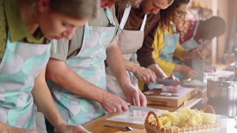 estudiantes diversos y chef cortando carne de cerdo en la clase maestra de cocina