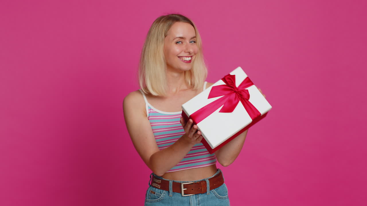 Happy smiling woman stretches out hands presenting birthday gift box promotion holiday discount sale