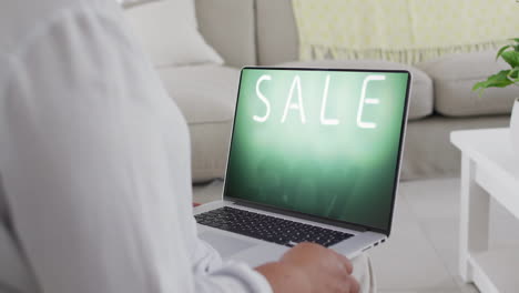 Mujer-Birracial-Usando-Laptop-En-Casa-Compras-En-Línea-Durante-La-Venta,-Cámara-Lenta