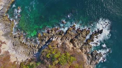 Overhead-Hover-View-of-Unique-Rocky-Coastline-with-Ocean-Waves-Crashing