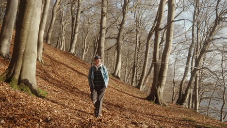 Junger-Mann,-Der-Durch-Einen-Hügeligen-Wald-Geht-Und-An-Der-Kamera-Vorbeigeht