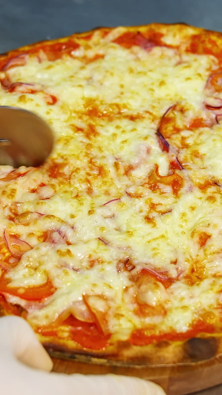 Chef cutting freshly baked pizza. Close up hand of chef baker cutting pizza at kitchen. Vertical video