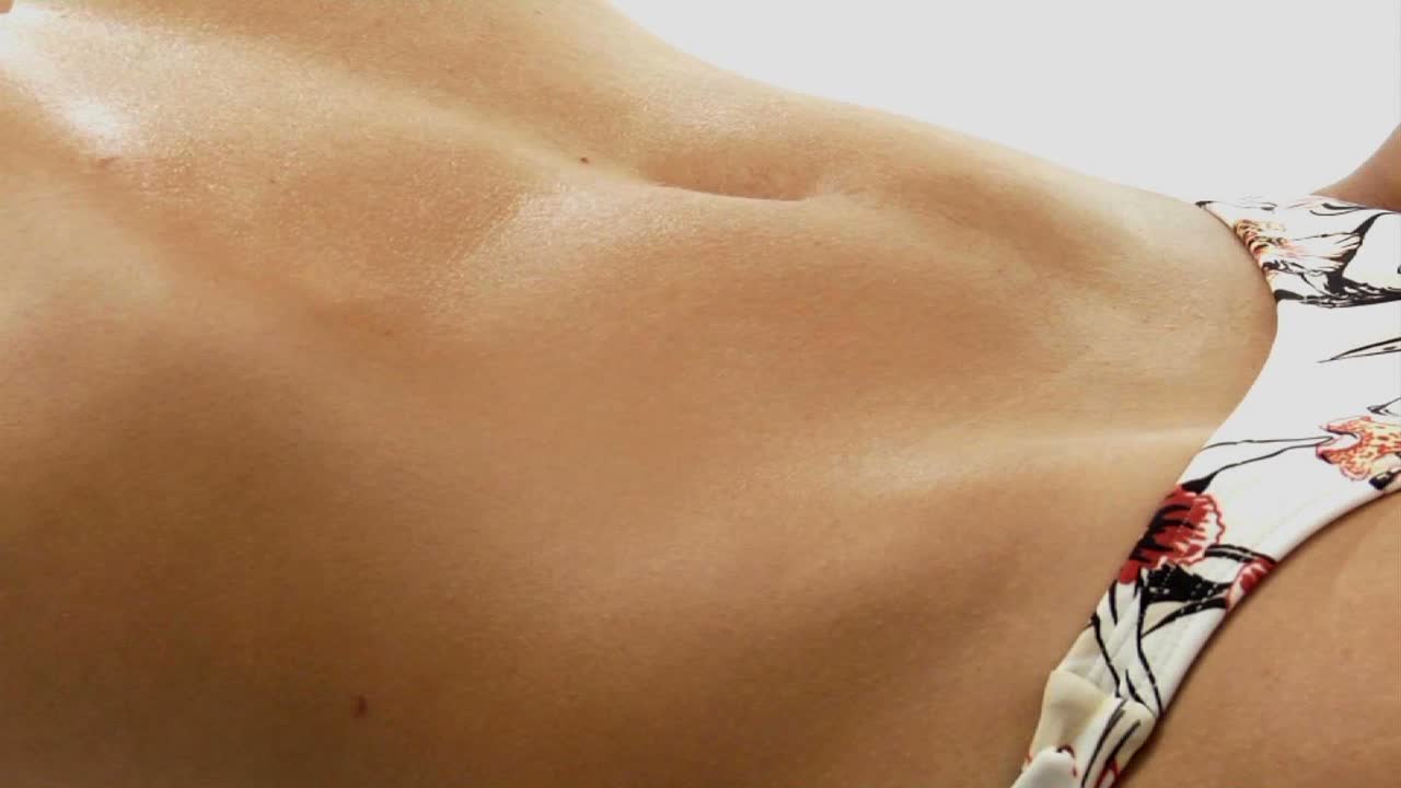 el estómago de una mujer respirando mientras usa la parte inferior de un bikini