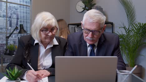 Senior-man-boss-with-woman-colleague-working-in-office,-secretary-relaxing-with-electric-fan