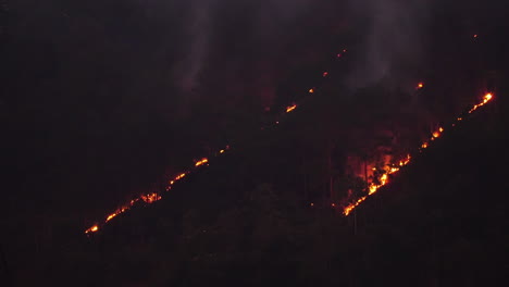 Burning-tropical-jungle-forest-hillside-in-Vietnam,-night-pan-right-view