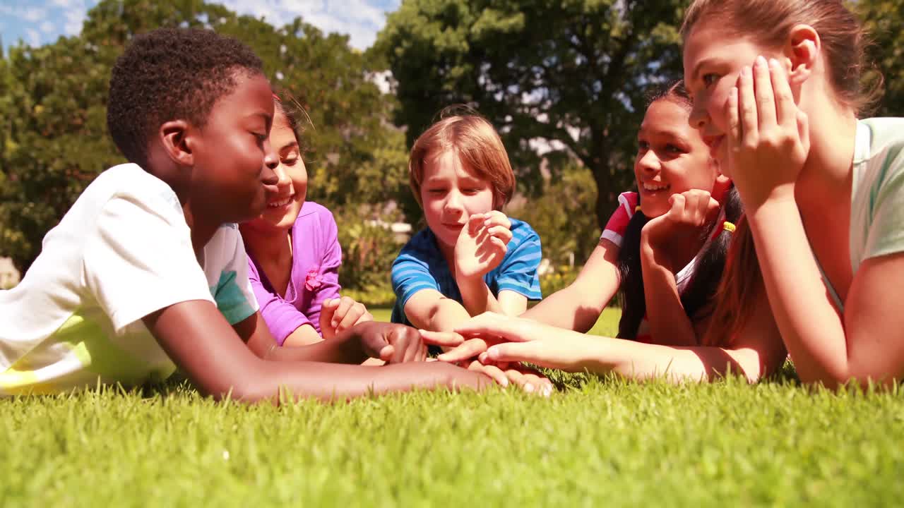 귀여운 학생들이 잔디에 누워서 손을 잡고
