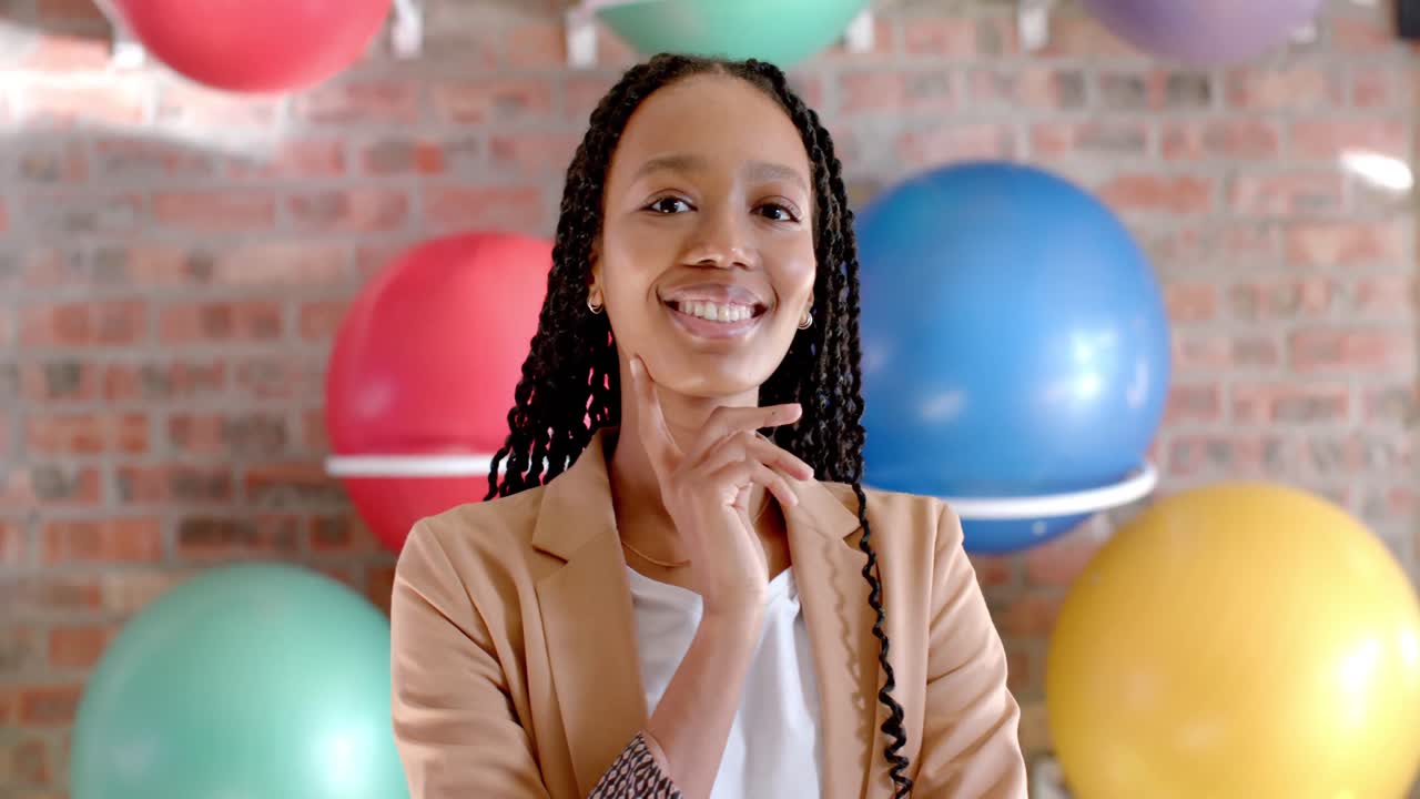 Portrait of happy african american casual businesswoman against wall with exercise balls in office