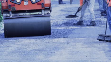 trabajadores de la ciudad y pequeña apisonadora asfaltando en la calle