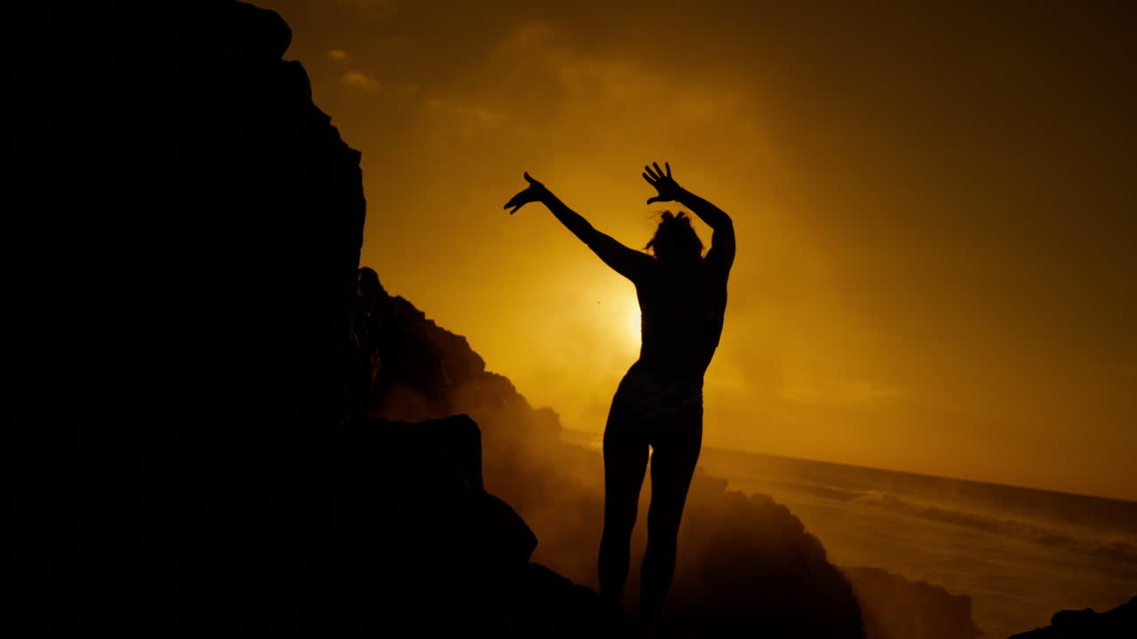 Woman Celebrating Sunrise over Volcanic Coastline