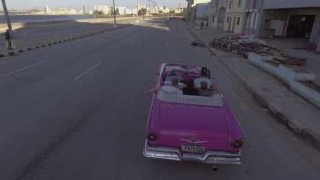 drone aerial of a group of tourists riding in a classic old car through the streets of havana cuba 1