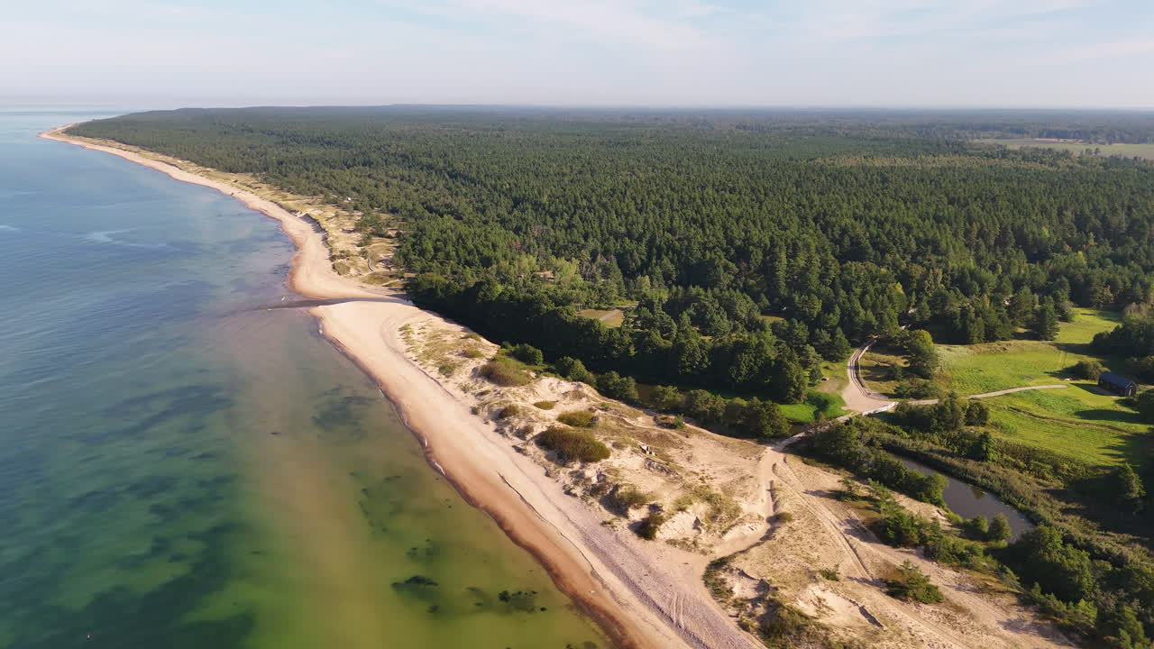 Aerial view of scenic coastline, sandy beach, river, and forest in Latvia.