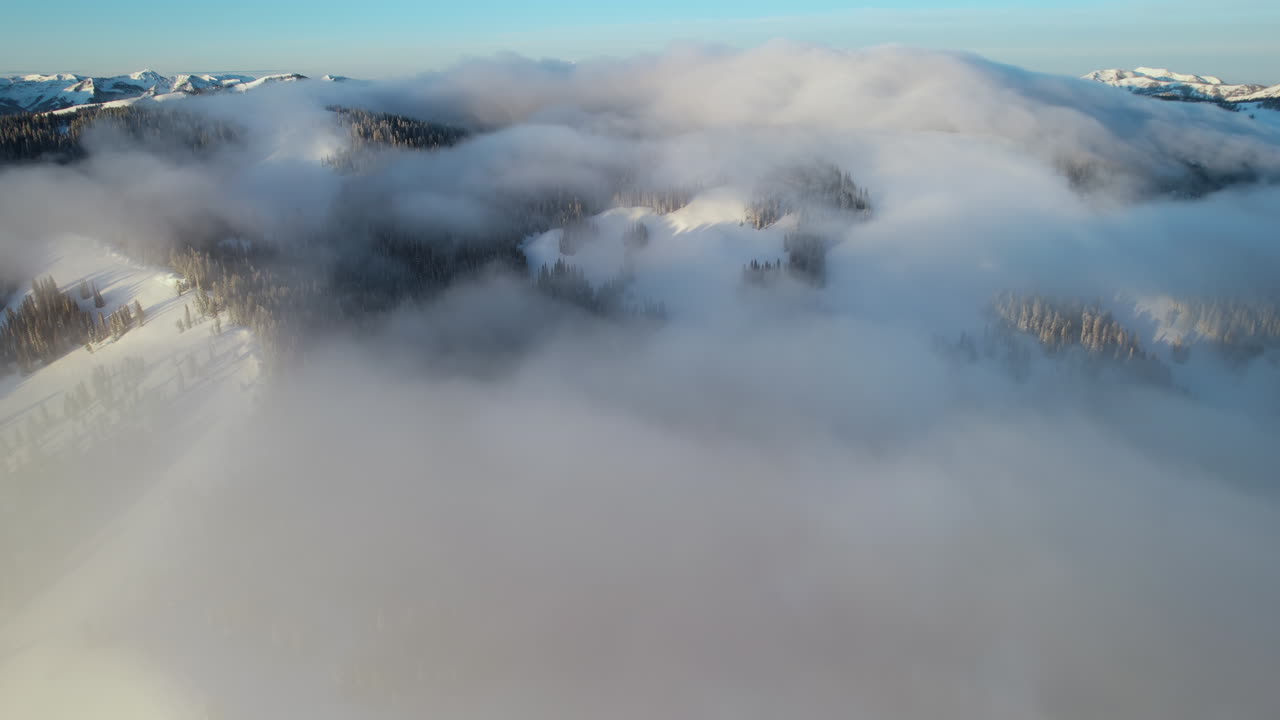 ⁇ 은 겨울 날에 와이오밍 미국 테튼 산맥의 눈  ⁇ 인 언덕과 정상 위의 구름의 공중 전망