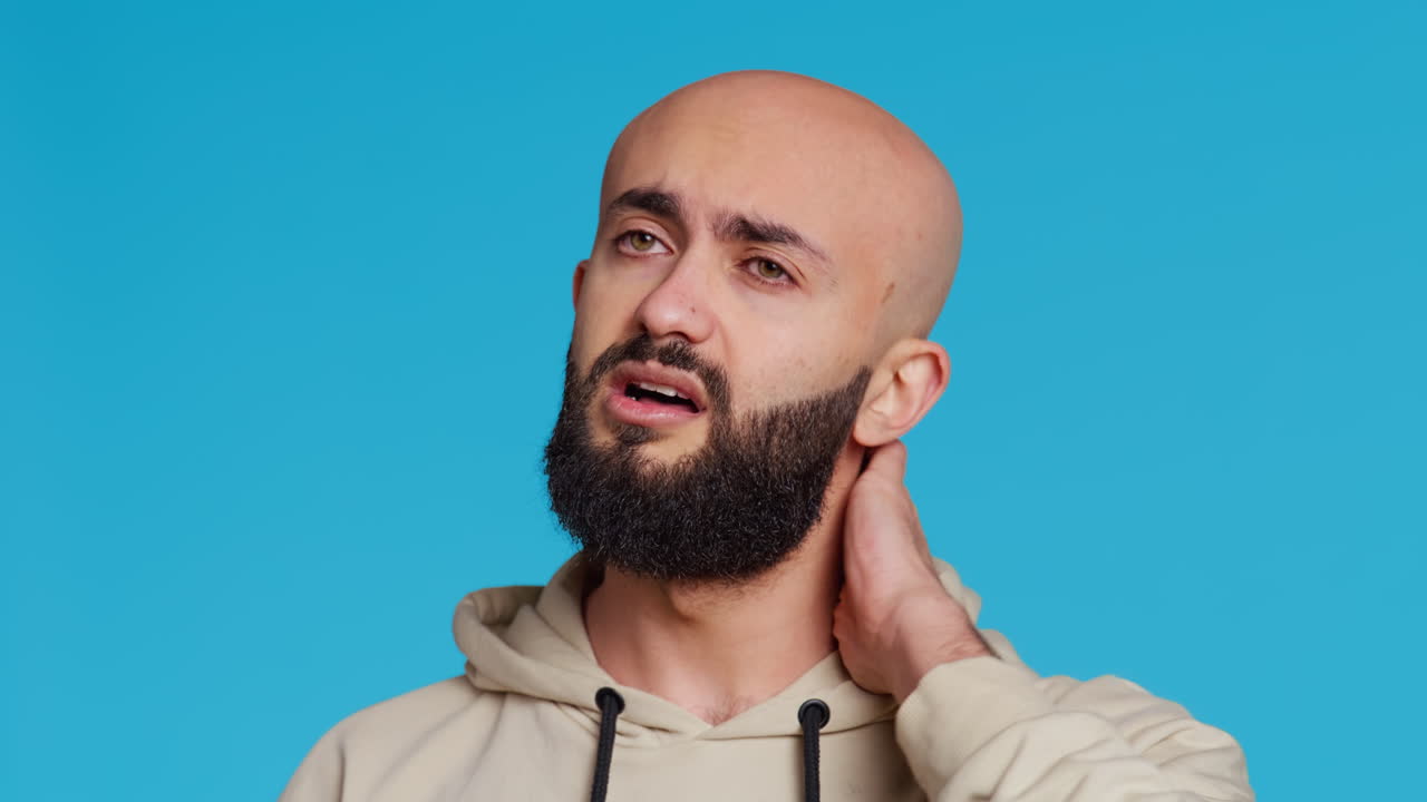 병든 중동인 남자가 카메라 앞에서 목통을 고 있습니다.