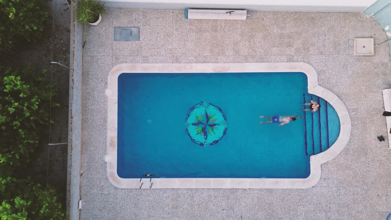 Familie med mor og søn svømmer i pool, luftfoto