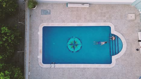 Mother-and-son-family-swimming-at-pool-aerial-view