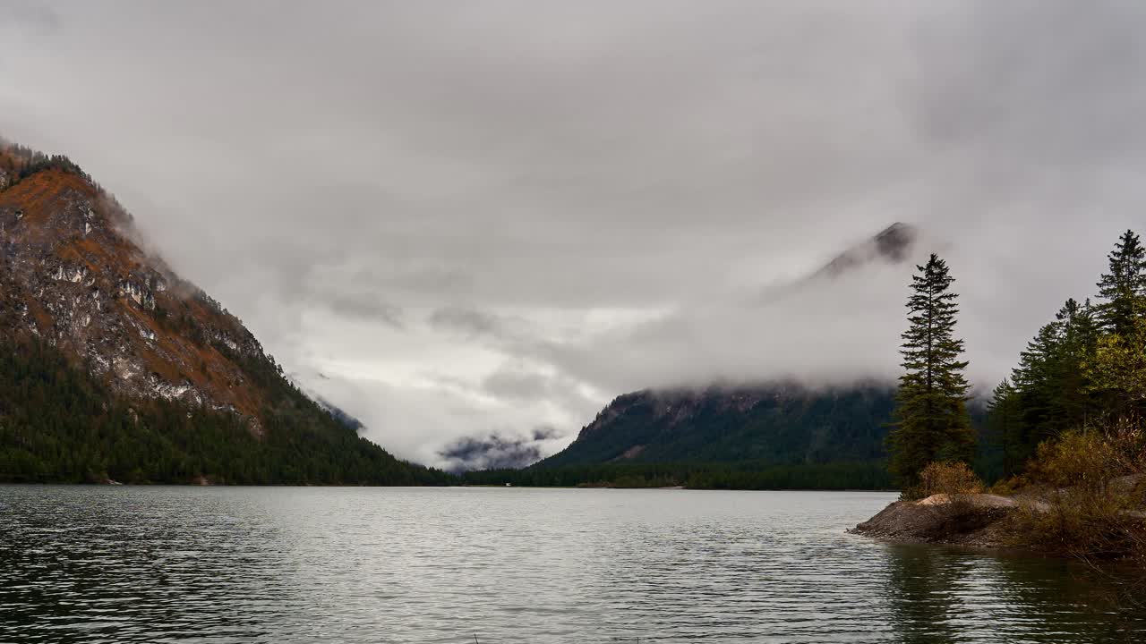 Swirling clouds slowly reveal alpine peaks in Heiterwangersee, a lake in Tirol, Austria