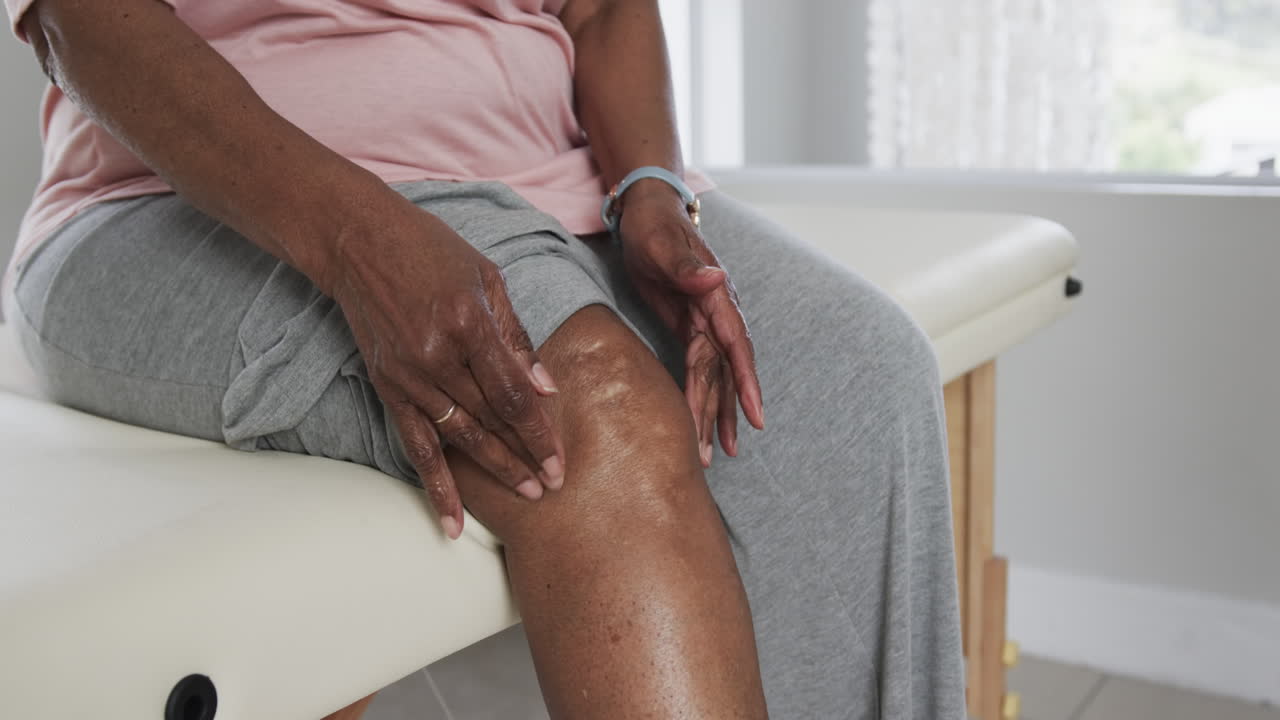 Senior african american woman touching her knee, copy space, slow motion