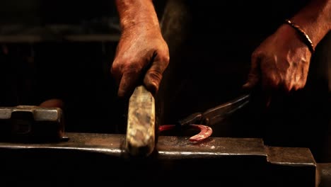 Mid-section-of-blacksmith-using-wire-brush-on-horseshoe