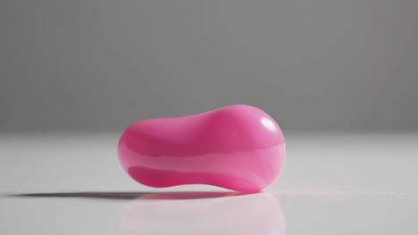 minimalist video concept featuring a glossy pink heart-shaped object on a flat surface