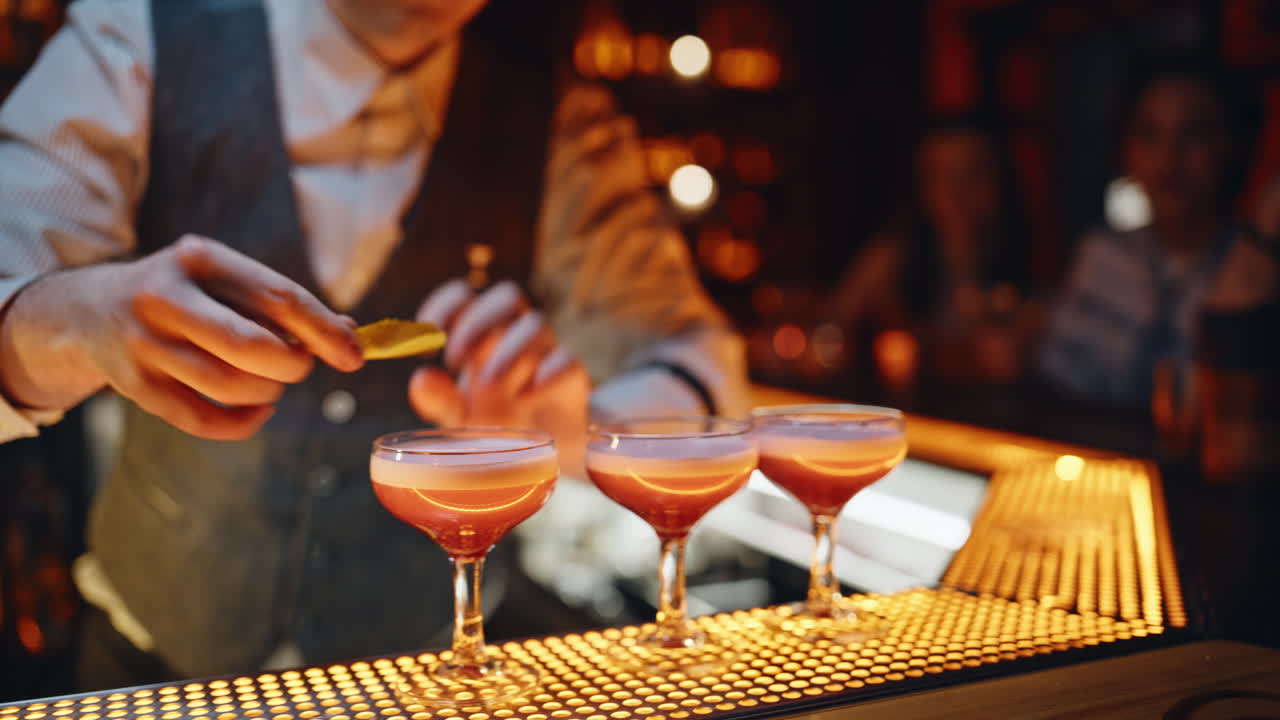 Primo piano di un barman che sprema limoni in bicchieri con cocktail sul bancone del bar