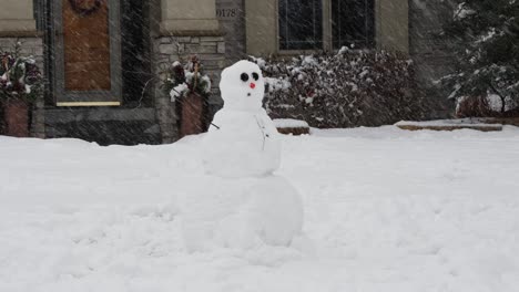 hombre de nieve en el patio delantero de una casa en un día de nieve en medio del invierno