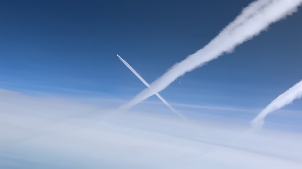 青い空に複数の白い飛行機雲が広がる空中コックピットからの眺め。上層大気中を高度10000mで飛行中に撮影。