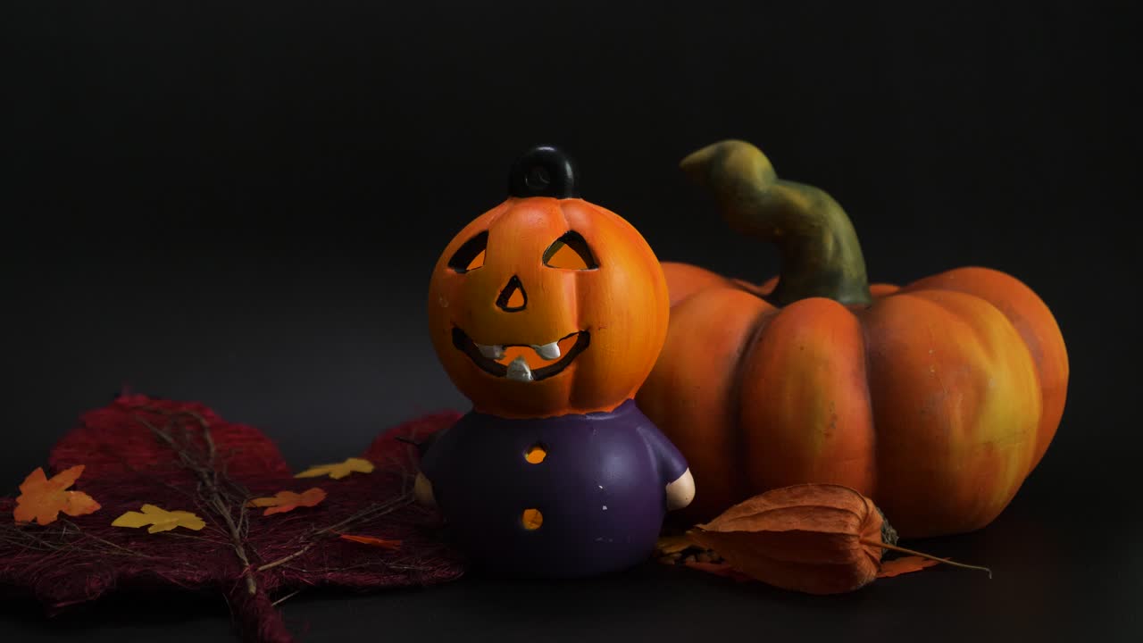 decoración de otoño de halloween con cabeza de calabaza de fiesta iluminada otra calabaza artificial y hojas de colores naranja sobre fondo negro